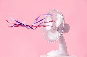 Witte ventilator met kleurrijke linten op een roze achtergrond
