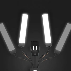 Een professionele LED-lamp met dubbele arm en instelbare kleurtemperatuur, gemonteerd op een stevige driepoot, met in het midden een houder voor een mobiele telefoon om het aanbrengen van wimperextensions vast te leggen.