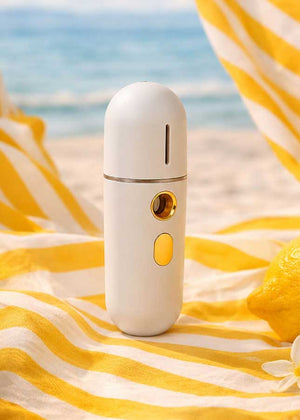 Luxury Lashes Nano Mister voor wimperextensions in zomerse beach setting met gele strepen, citroen en zeezicht op de achtergrond.